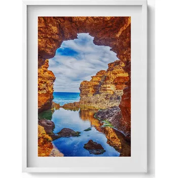 Obraz Elegantní obraz do obýváku v bílém rámu Pohled zpod skal na moře 50x70 cm