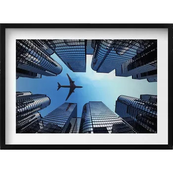 Obraz Dekorativní obraz v černém rámu do obýváku Letadlo nad budovami 70x50 cm