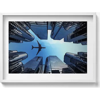 Obraz Dekorativní obraz v bílém rámu do obýváku Letadlo nad budovami 70x50 cm